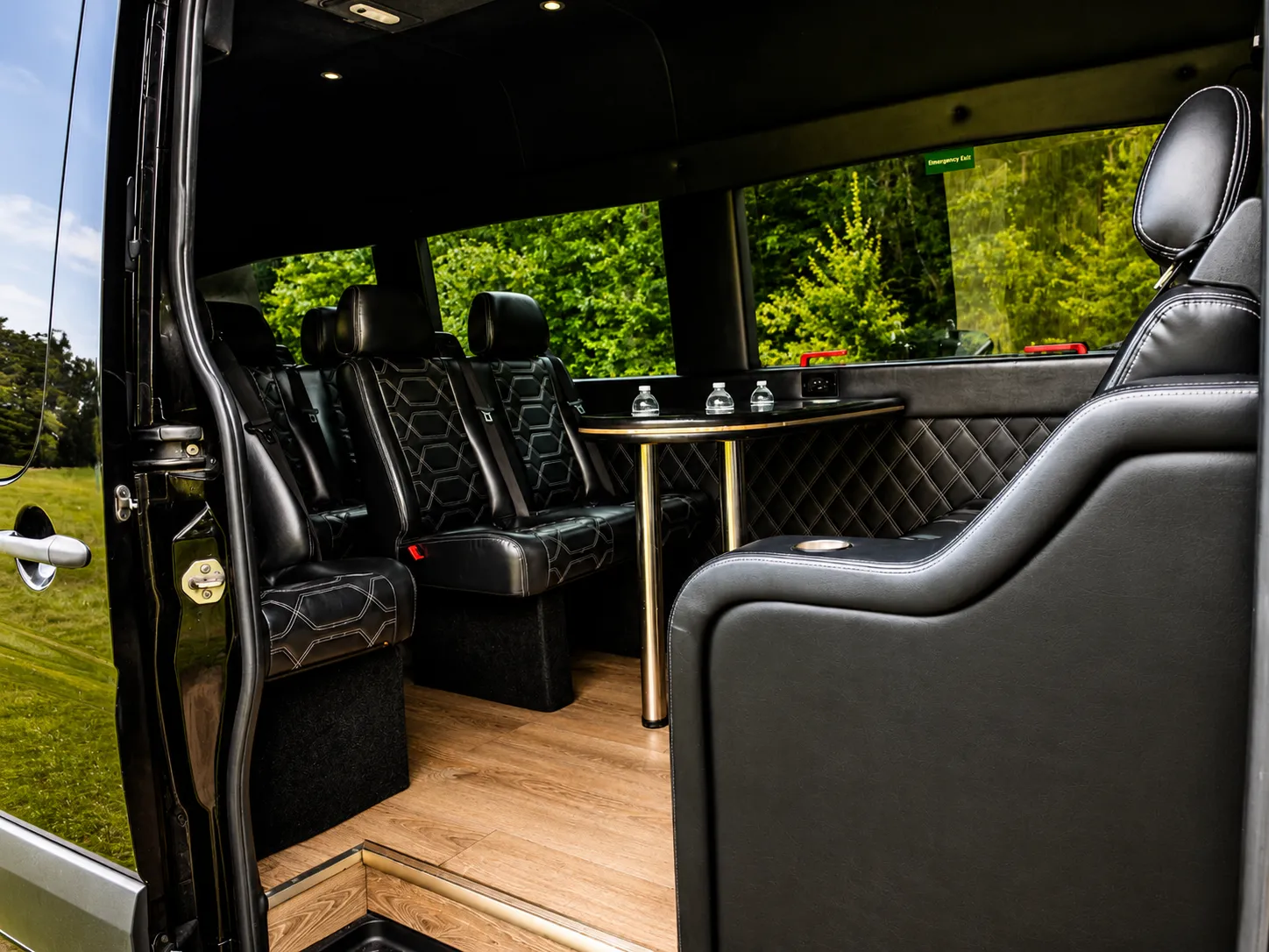 The Executive Sprinter Van from its open side door: a rear bench, facing seats and a fixed table