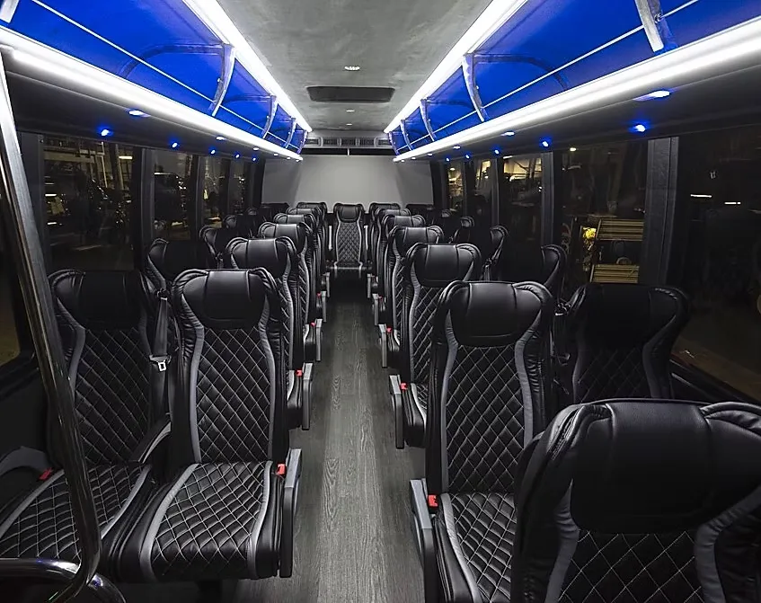 The Small Coach Bus cabin under its blue ceiling lighting, quilted seats either side of the aisle