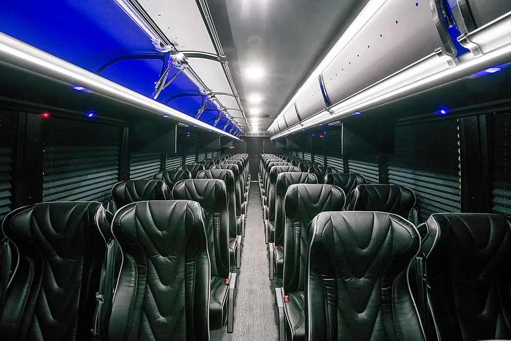 The Coach Bus cabin under its blue ceiling lighting, looking down the aisle to the back row