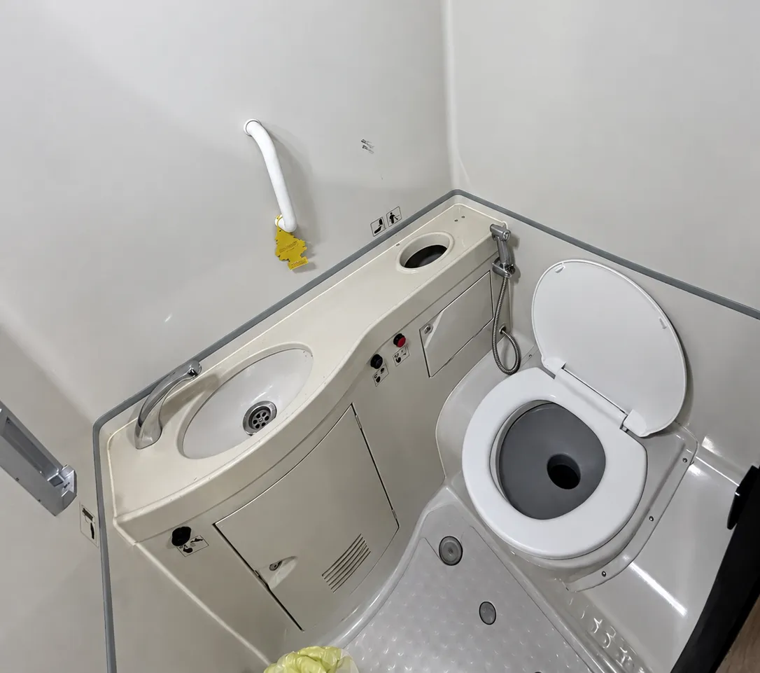 Onboard coach lavatory with a toilet, compact sink, and grab rail