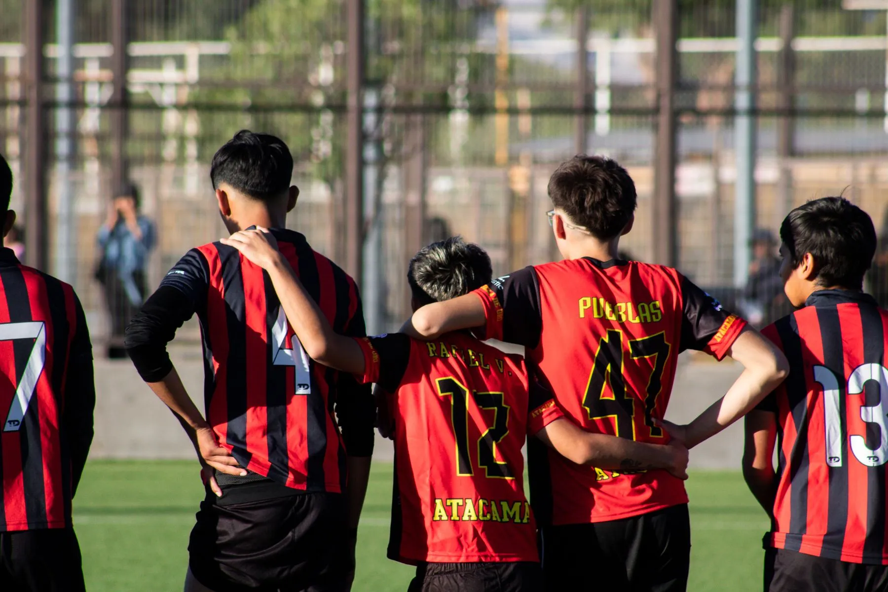 A youth soccer team huddled together on the field